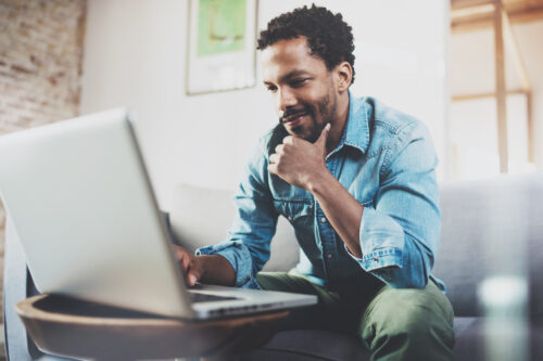 A Black man browsing on his laptop to choose a membership database.