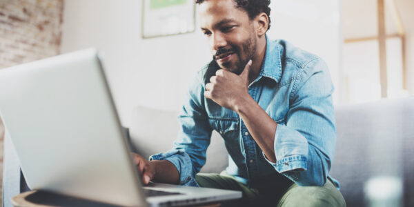 A Black man browsing on his laptop to choose a membership database.