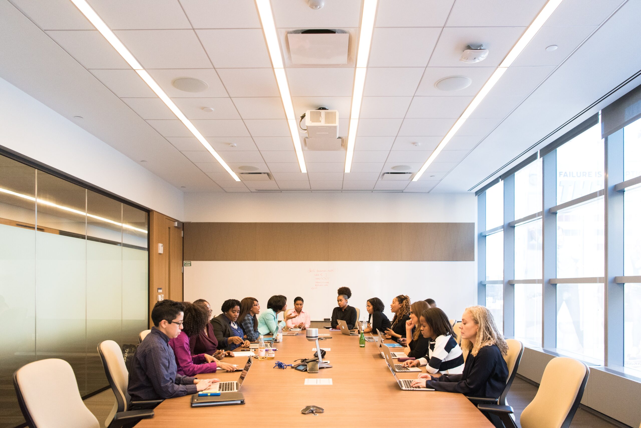 Members gathered in a conference room for a meeting, making notes on important takeaways.