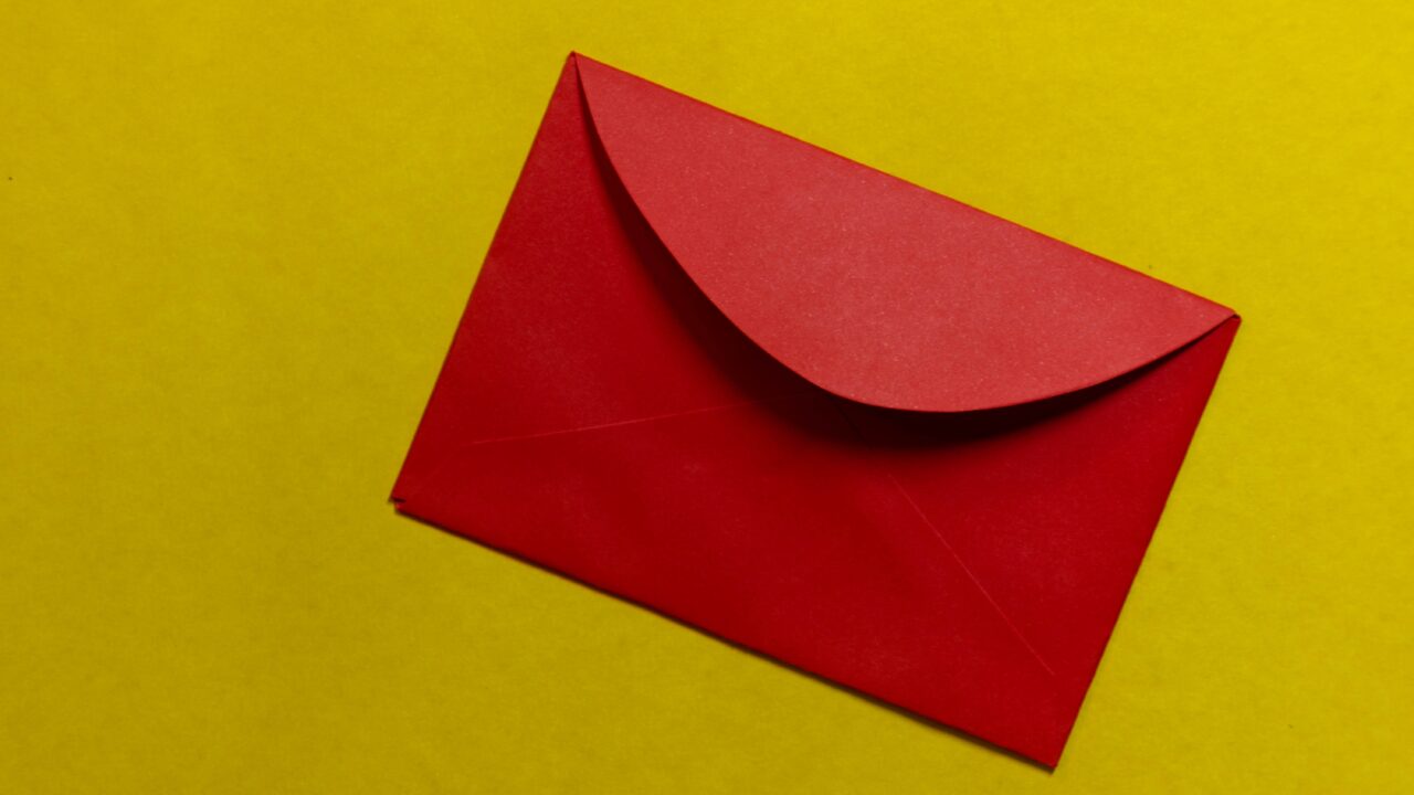 A red envelope containing a member newsletter on a yellow background.