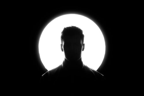 A bright spotlight backlighting a member's silhouette against a black background.