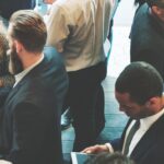 
                            A group of people socializing at an association event and conversing with new members.                            