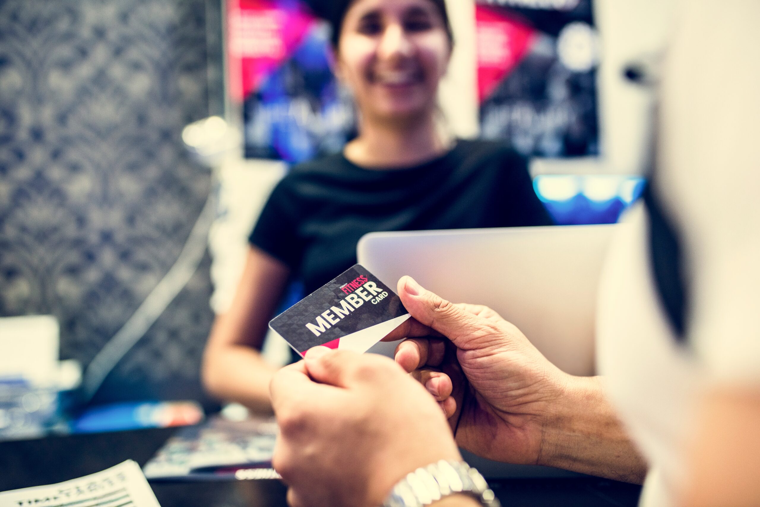 membership card being handed off to woman at computer