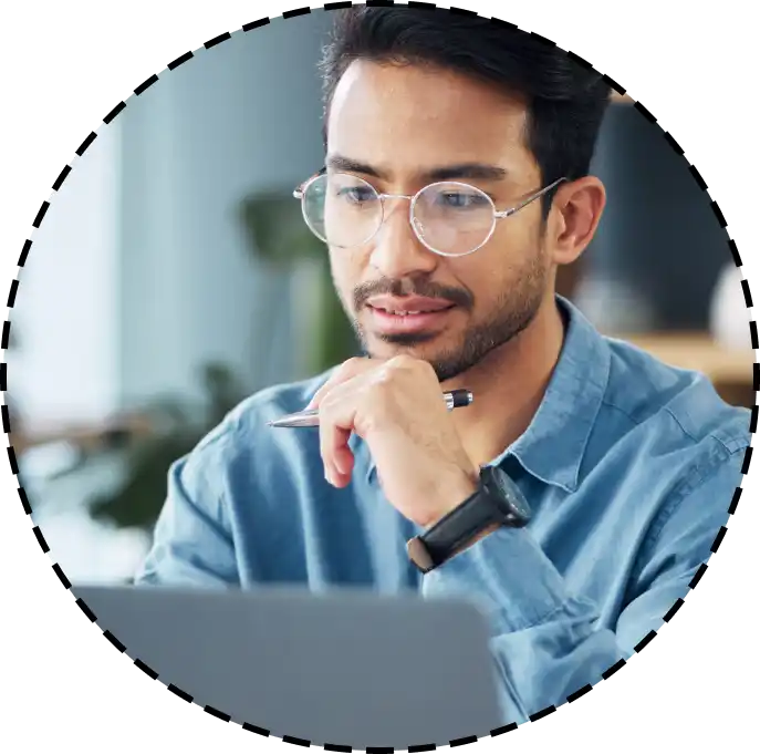 man holding a pen while looking at a computer