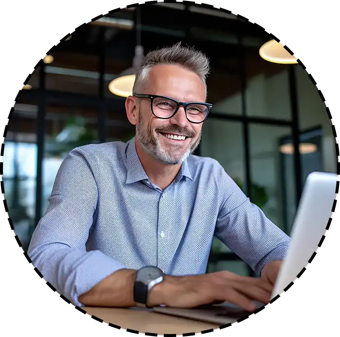 man smiles while working on a laptop